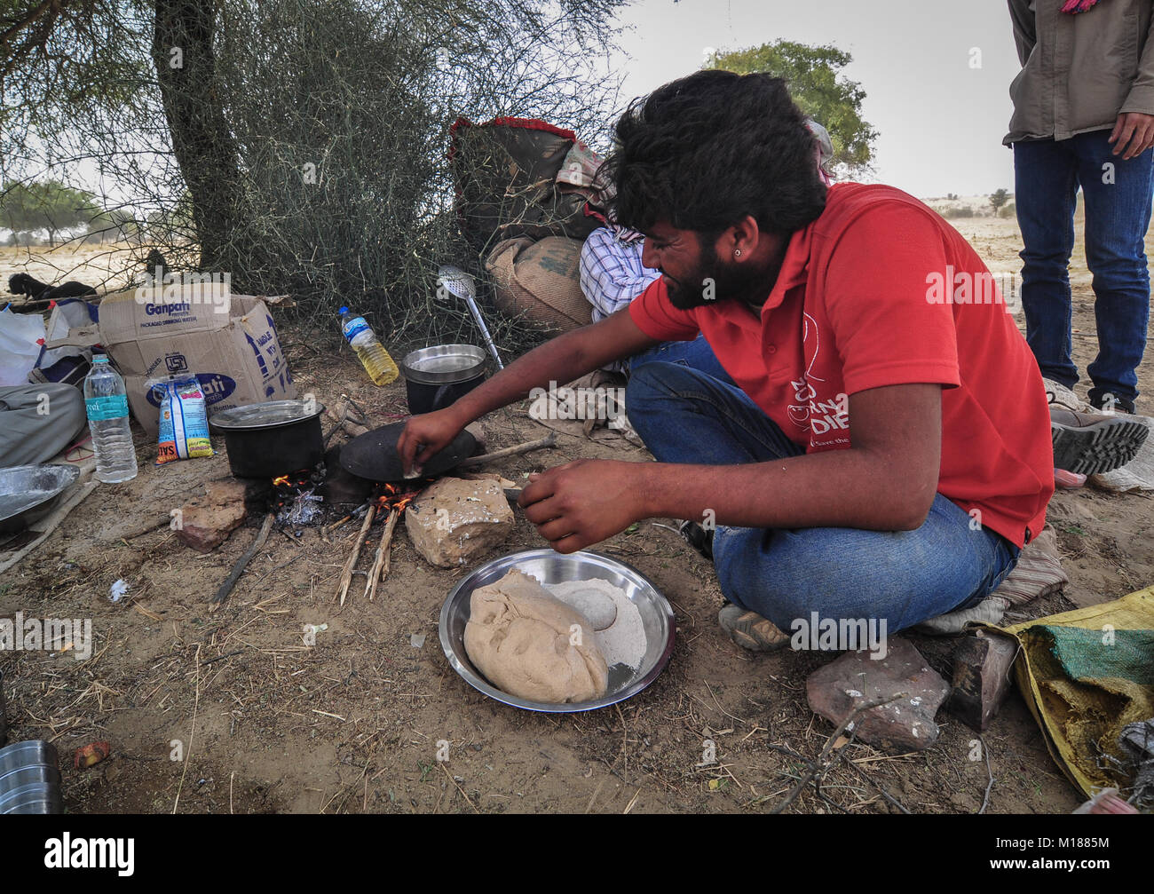 Jaisalmer, India - Mar 4, 2012. A man cooks meal during camel safari in Jaisalmer, India. Camel safaris in That desert are very popular among tourists Stock Photo