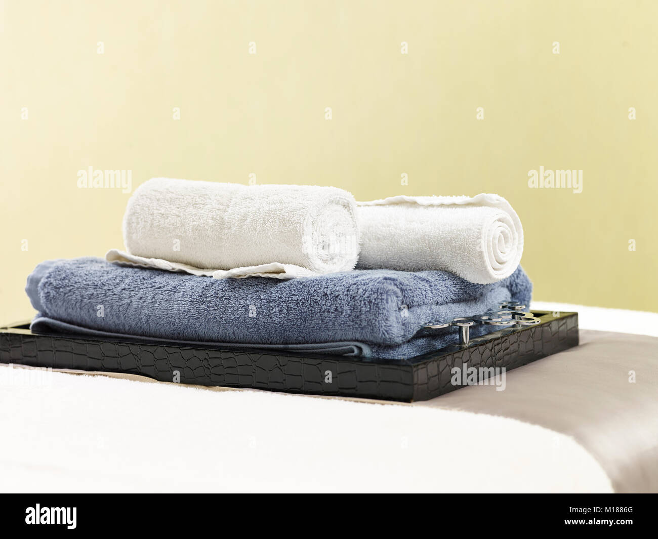 rolled towels on a tray on massage bed in beauty spa or health club. Stock Photo