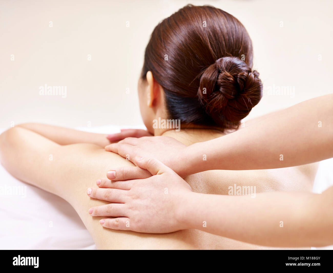 hands of a masseur massaging back and shoulder of a young asian woman Stock Photo