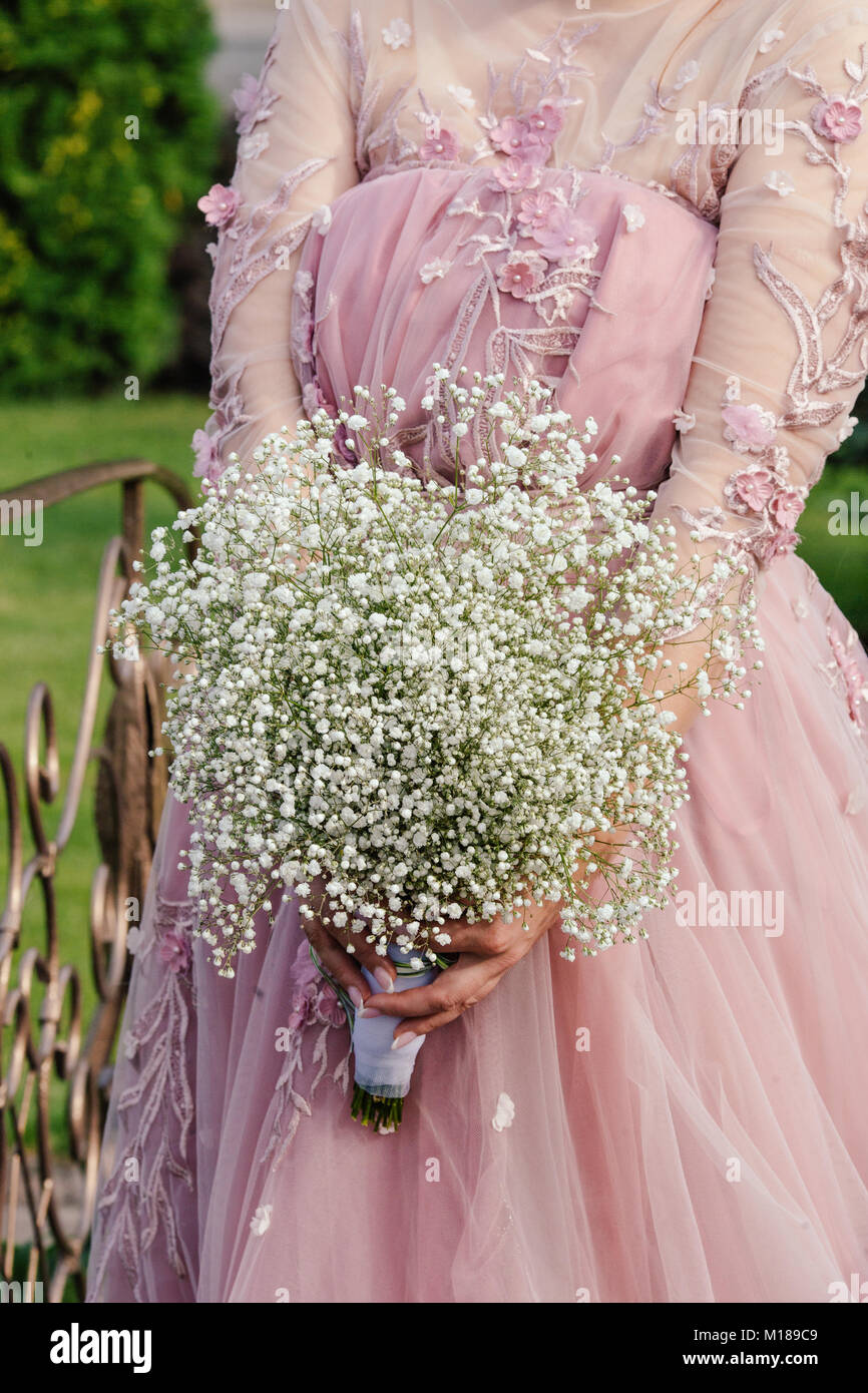 The bride in a pink dress is holding a bouquet of gypsophila Stock