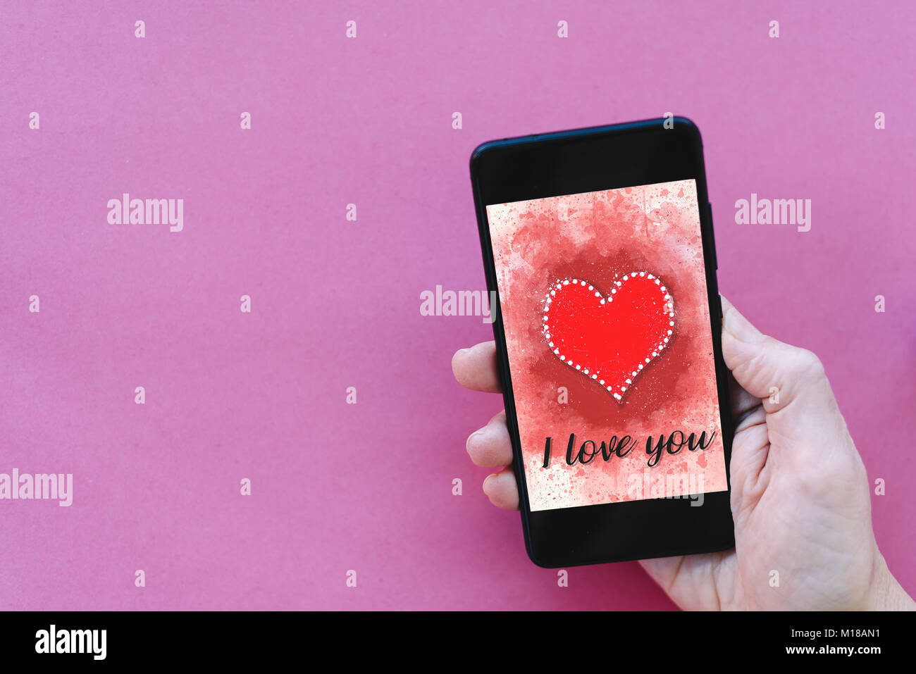 Valentines day sale background with heart illustration with the words I Love You on smartphone screen mockup on pink background with woman hand holdin Stock Photo