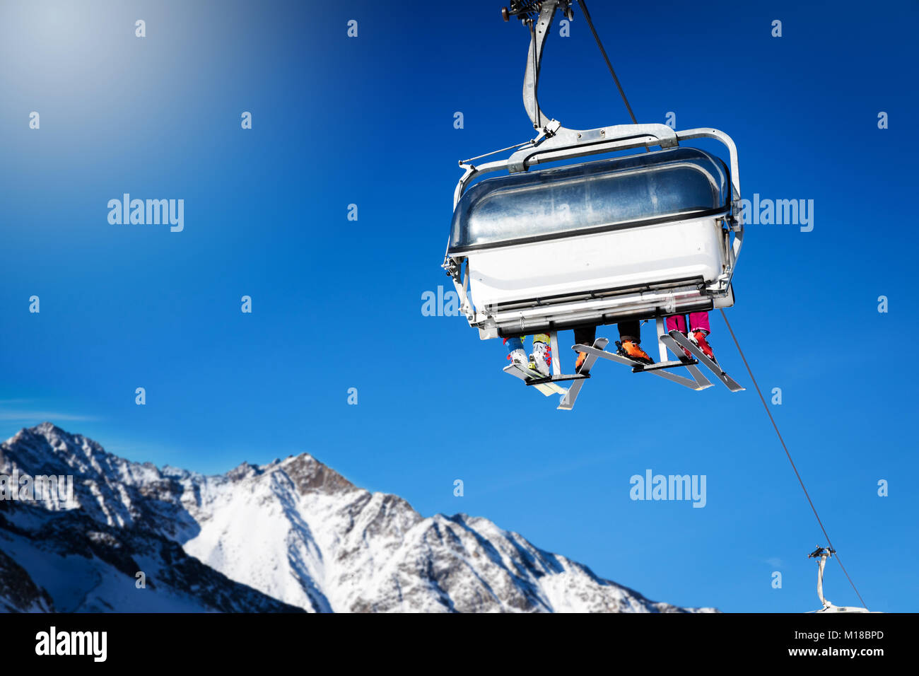 skiers in a chairlift against blue sunny sky at ski resort Stock Photo