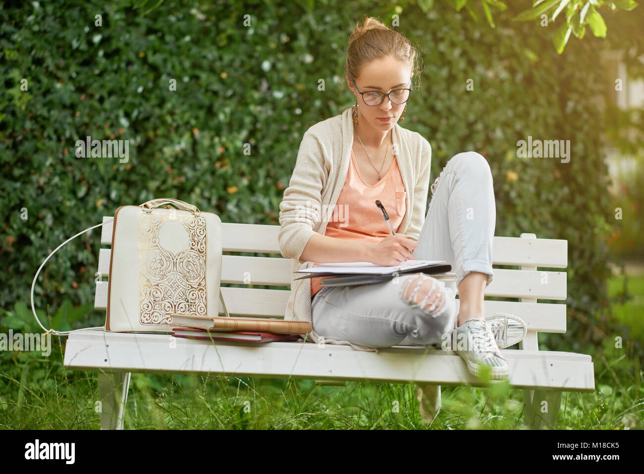 Young student writes on the park s bench Stock Photo
