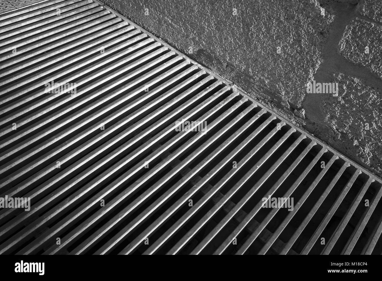 Steel grating of urban drainage system near concrete wall, abstract background photo Stock Photo