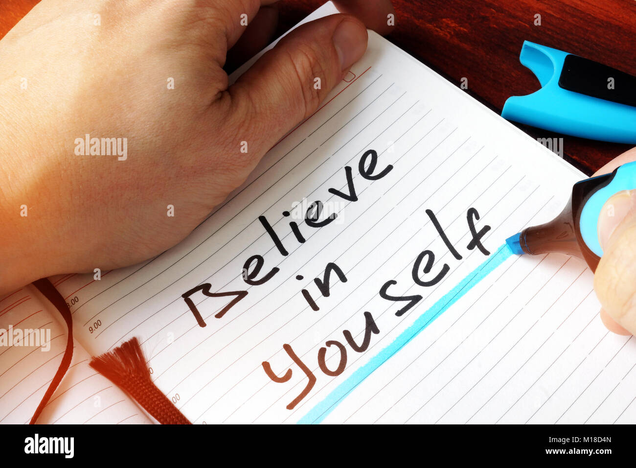Man writing Believe In Yourself in the note. Stock Photo