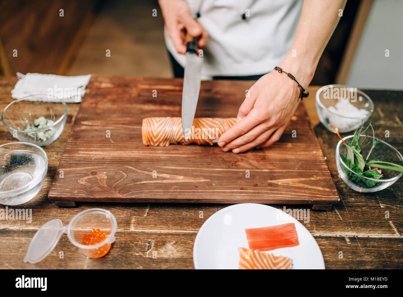 Male person cooking seafood on wooden table, japanese food preparation
