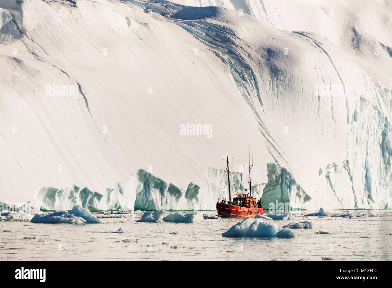 Red boat in front of gigantic iceberg,West Greenland,Greenland Stock Photo