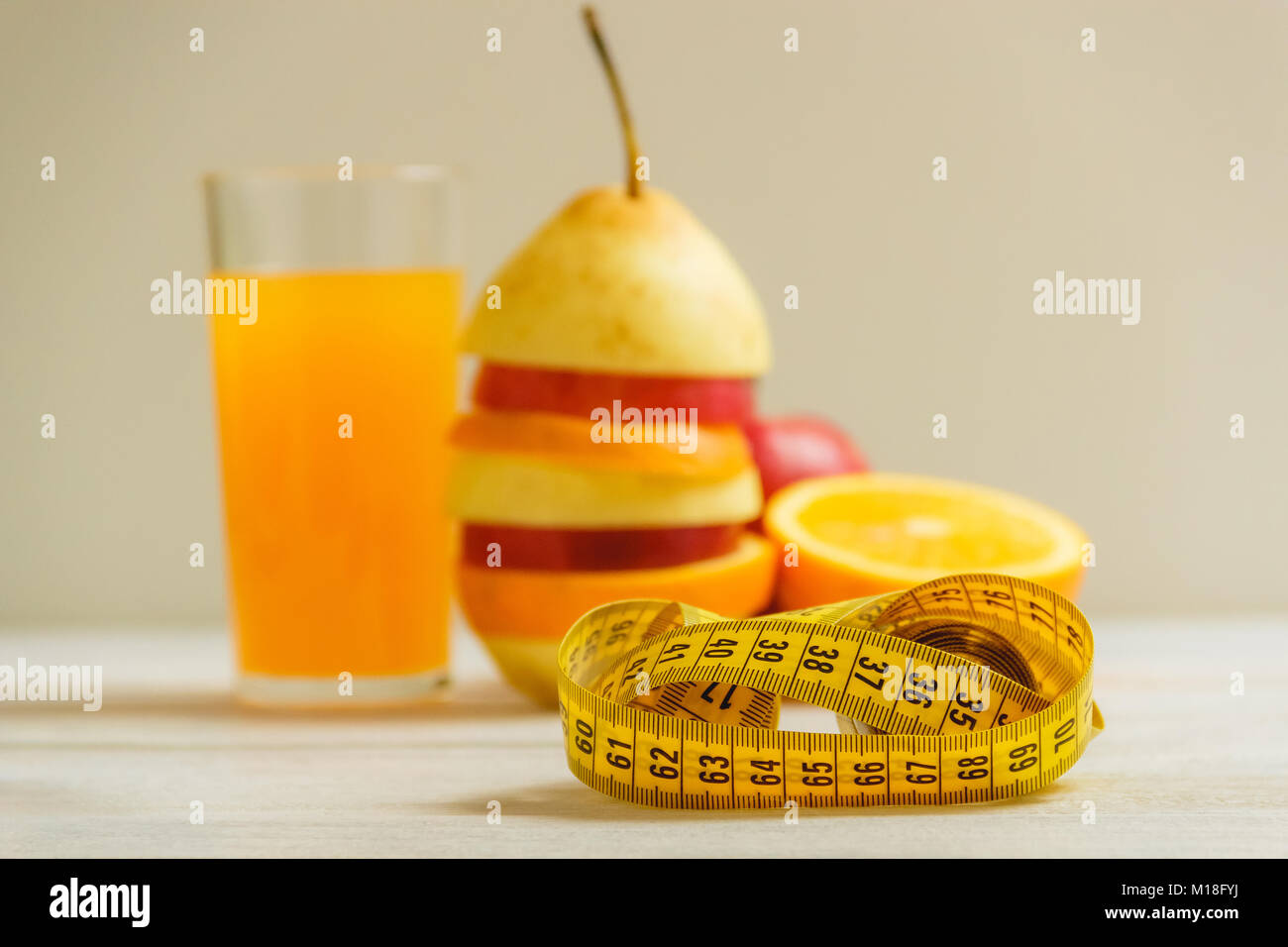 Measure tape and fresh fruit on wooden table. Healthy lifestyle diet with fresh fruits. Stock Photo