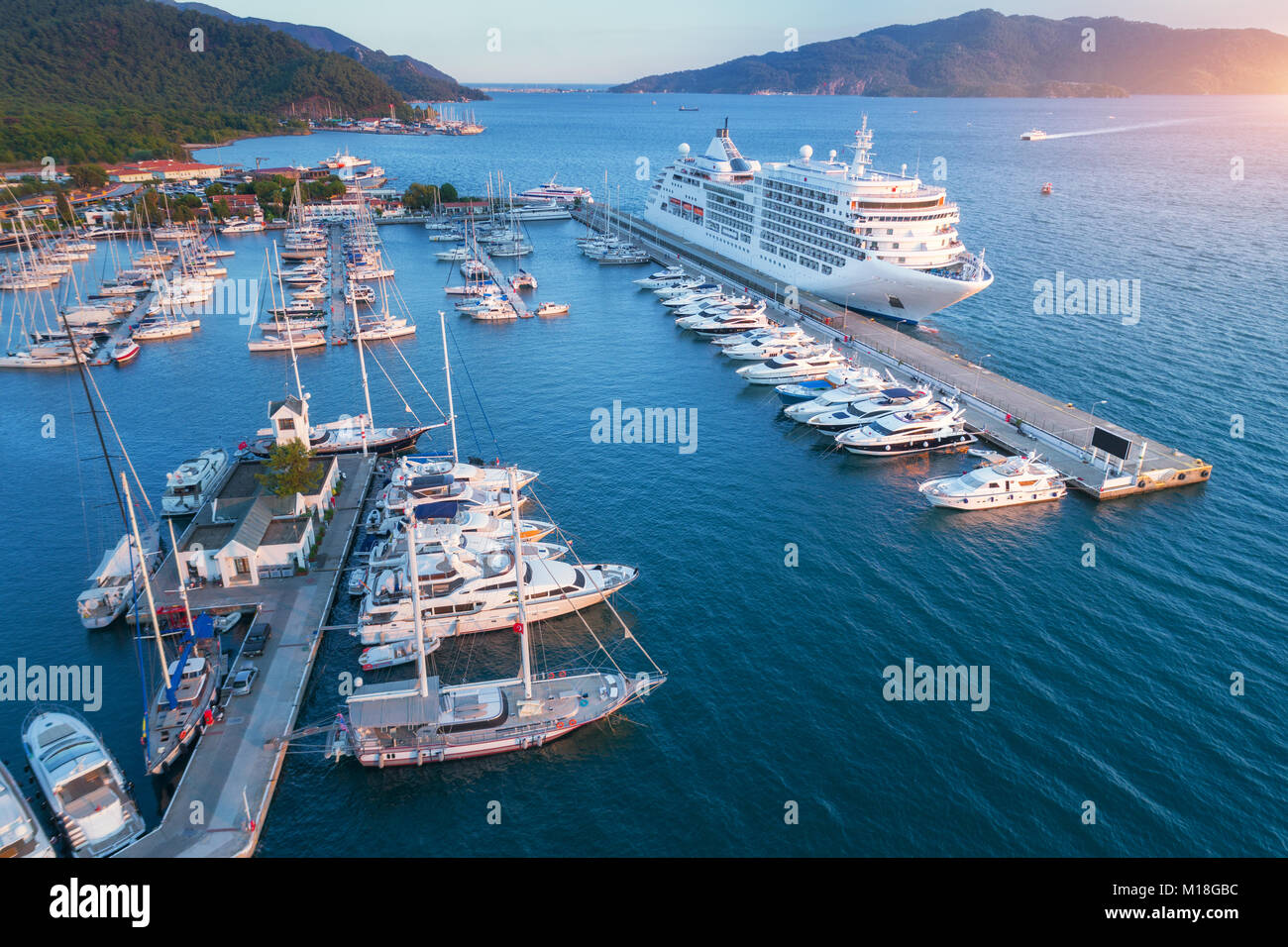 Cruise ship at harbor. Aerial view of beautiful large white ship at sunset. Colorful landscape with boats in marina bay, sea, colorful sky. Top view f Stock Photo