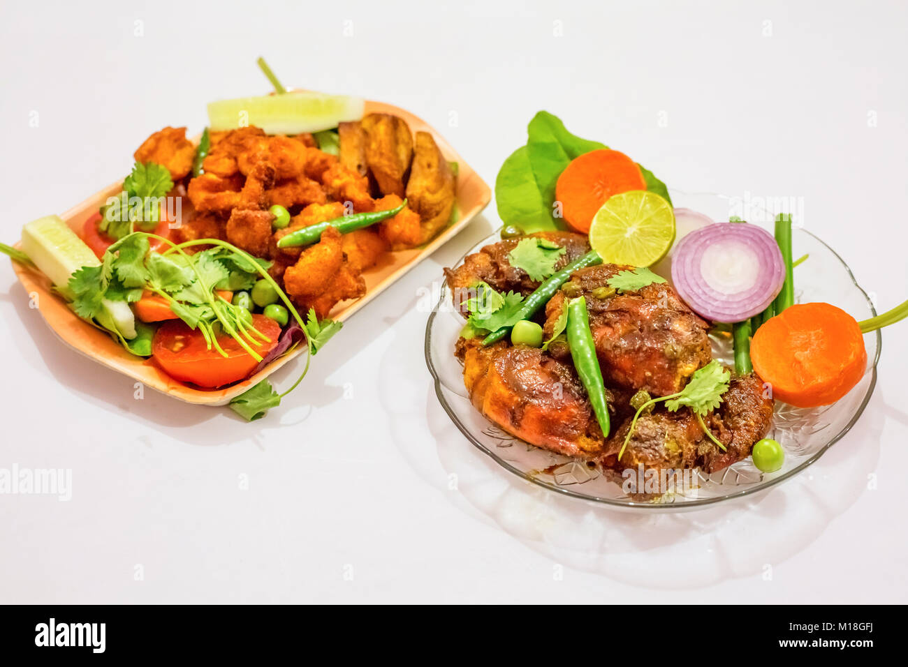 Delicious spicy Indian starter dish of deep fried crispy prawn and boneless chicken pakora. Bengali Indian cuisine isolated on white background. Stock Photo