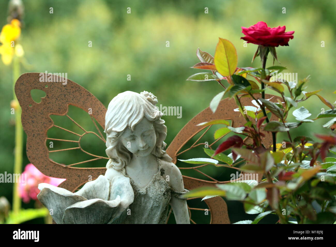 A stone fairy guards the garden. Stock Photo