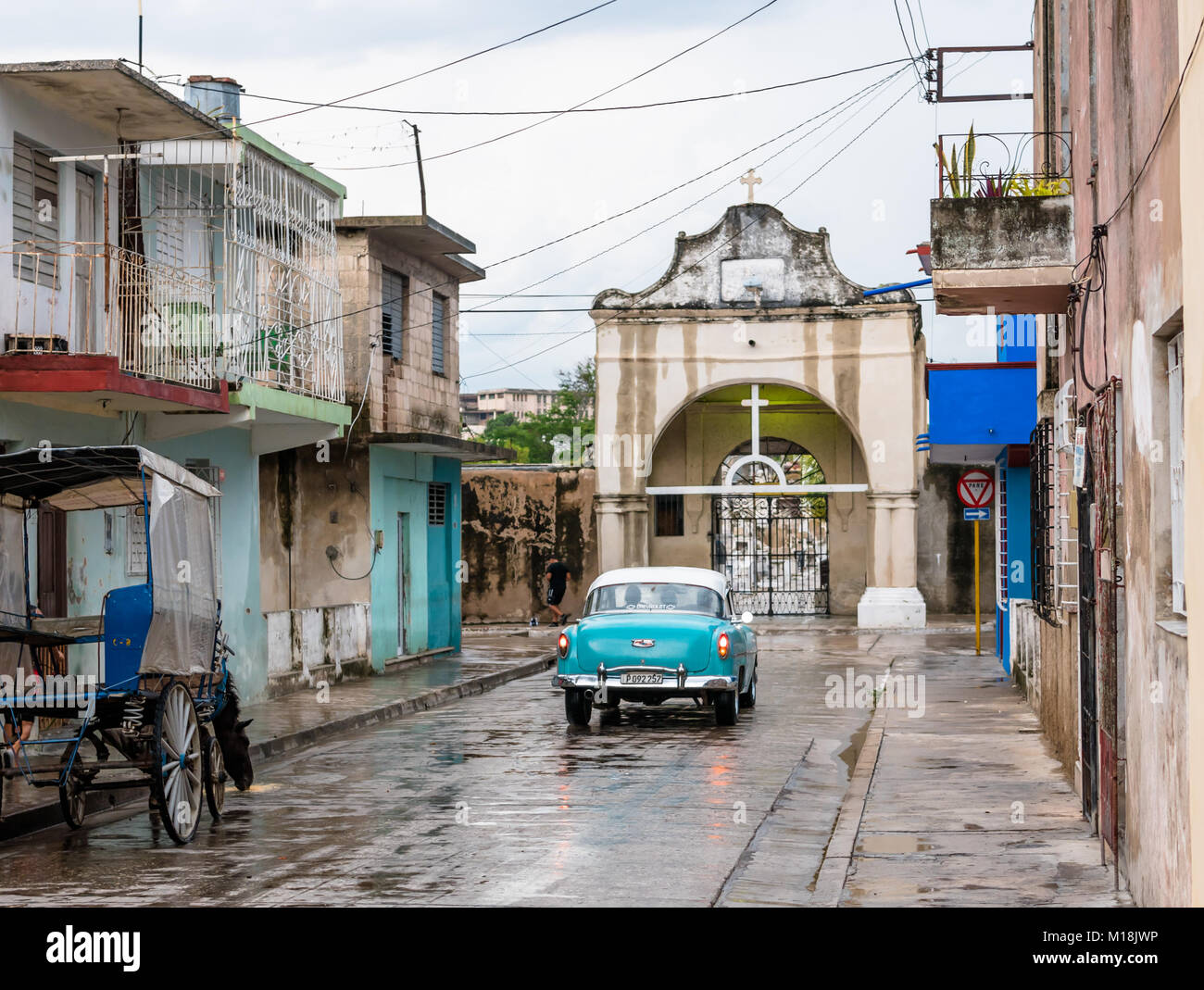 Holguin, Cuba - August 31, 2017: View of an American classic car driving towards the entrance to a cemetery Stock Photo