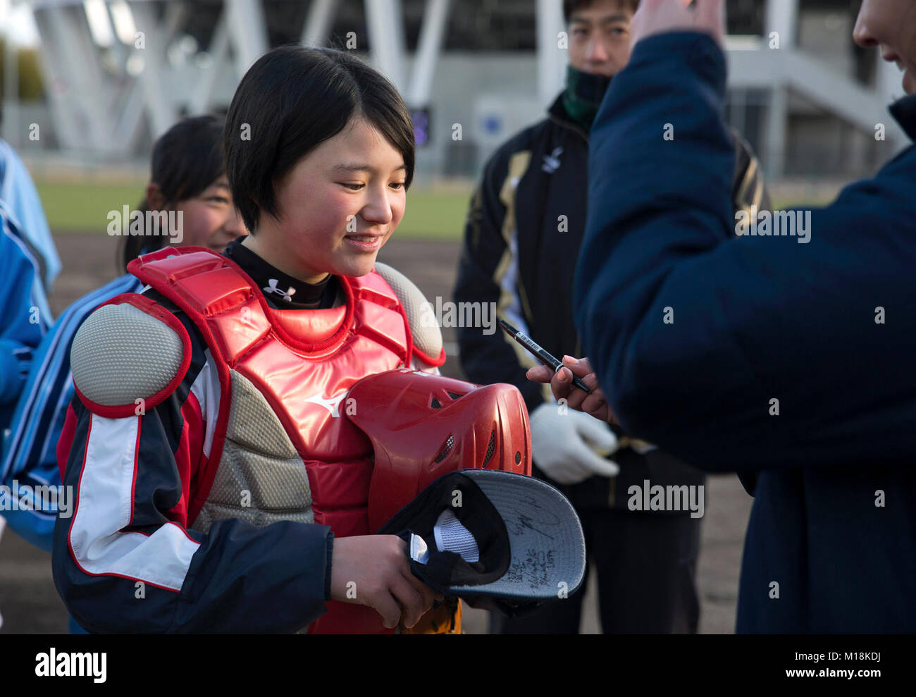 Valerie Arioto, an infielder with the U.S.A. National Women’s Softball team signs a softball cap for a child from the Higashi Middle School softball team at the new Kizuna stadium in Iwakuni City, Japan, Jan. 25, 2018. The U.S.A National Women’s Softball team visited players from middle and elementary schools to practice together. The intent of the U.S. softball team’s visit was to determine if the stadium is suitable for the team to practice and play future games at. The stadium is a hallmark of what the U.S.-Japan friendship has accomplished in Iwakuni City. Everything from the dogwood trees Stock Photo