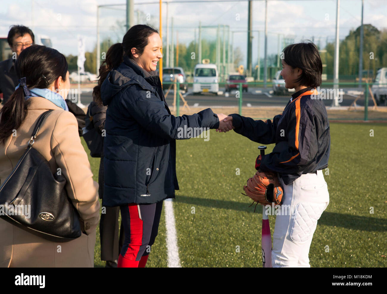 Valerie Arioto, an infielder with the U.S.A. National Women’s Softball team, greets a teenager from the Higashi Middle School softball team at the new Kizuna stadium in Iwakuni City, Japan, Jan. 25, 2018. The U.S. National Women’s Softball team visited players from middle and elementary schools to practice together. The intent of the U.S.A softball team’s visit was to determine if the stadium is suitable for the team to practice and play future games at. The stadium is a hallmark of what the U.S.-Japan friendship has accomplished in Iwakuni City. Everything from the dogwood trees planted just  Stock Photo