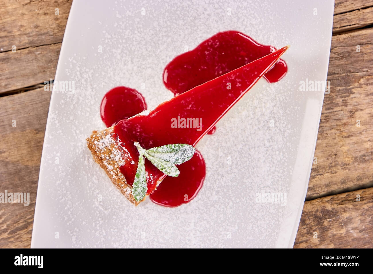 Slice of cheesecake with sweet red jam topping and flour Stock Photo