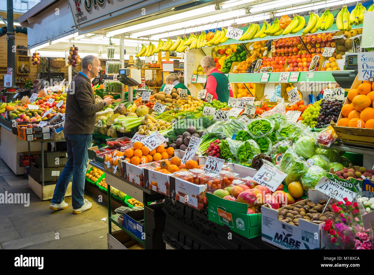 Man buying fruit  from an greengrocers stall  in the Victorian covered Market Darlington England stall shows 2018 prices. Stock Photo