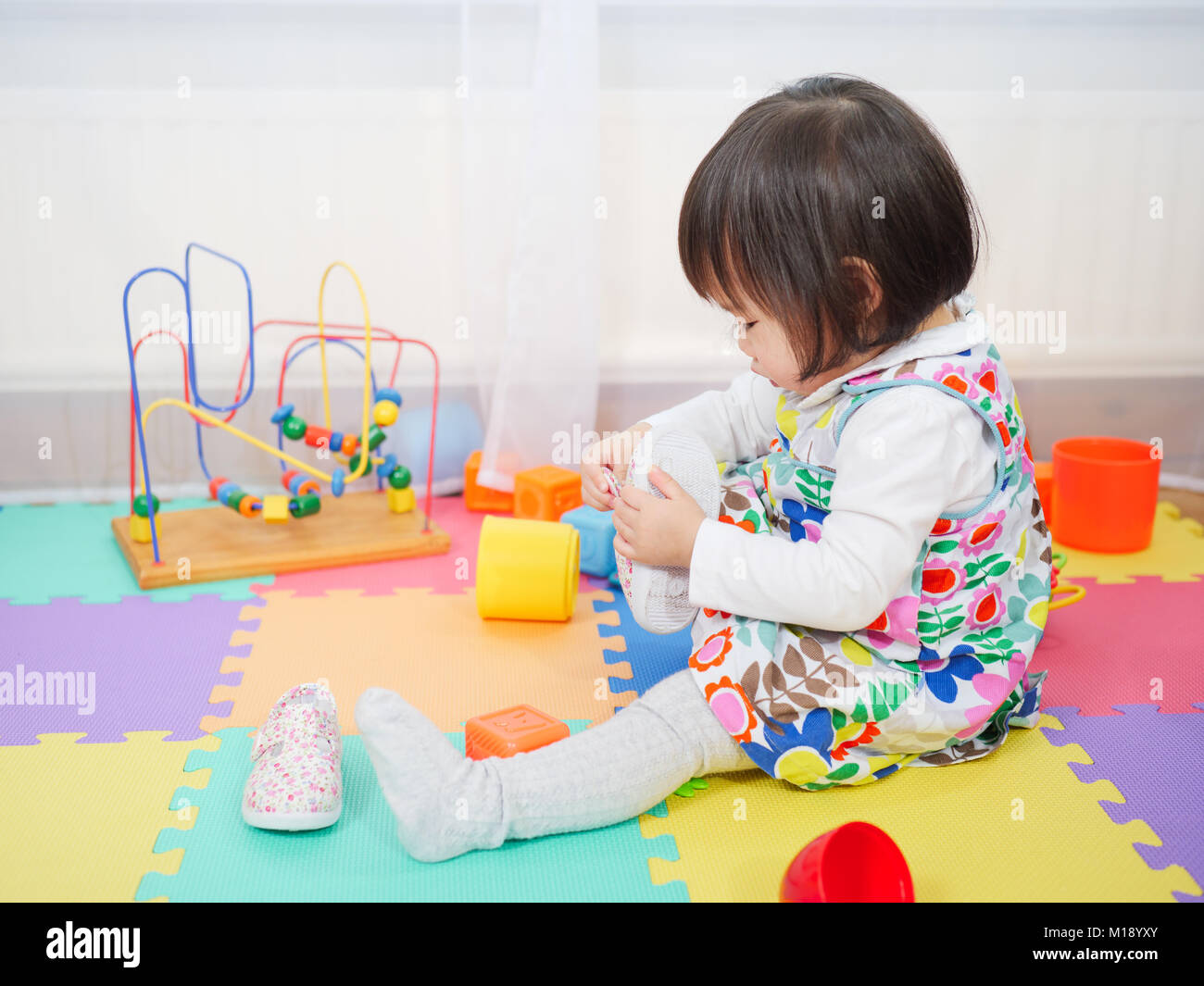 baby girl putting on her shoe Stock Photo Alamy