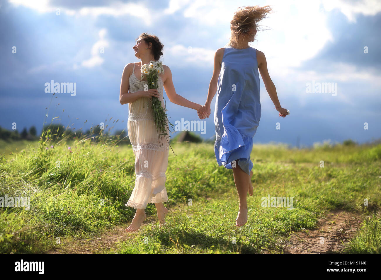 Young girls are walking in the field Stock Photo - Alamy