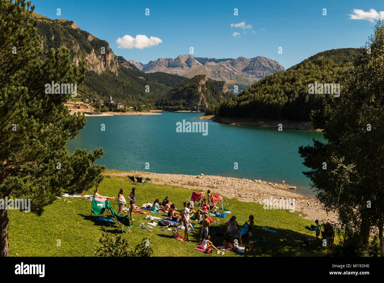 Picnickers by Lanuza resevoir with the Tendenera mountains beyond in the scenic Tena Valley. Sallent de Gallego; Pyrenees; Huesca Province; Spain Stock Photo