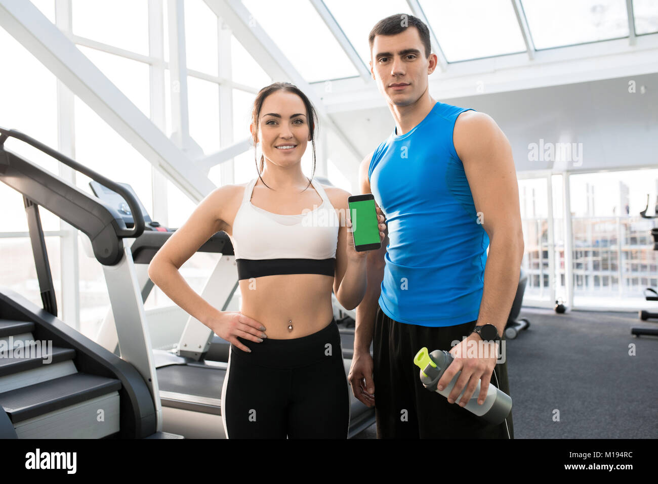 Couple showing smartphone with fitness app on sports ground Stock Photo Alamy