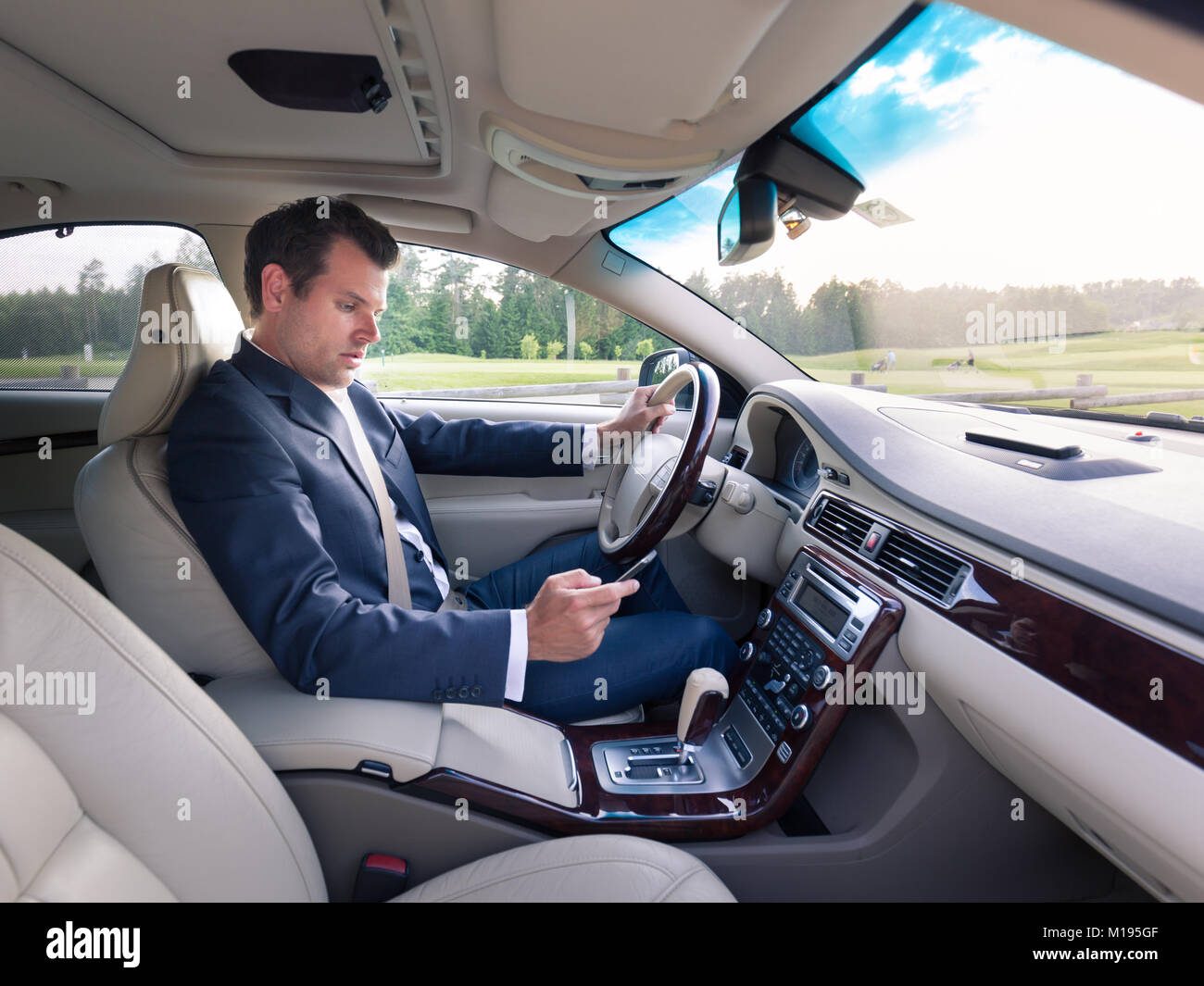 Businessman using cell phone and texting while driving not paying attention to the road. Dangerous texting and driving at the same time Stock Photo