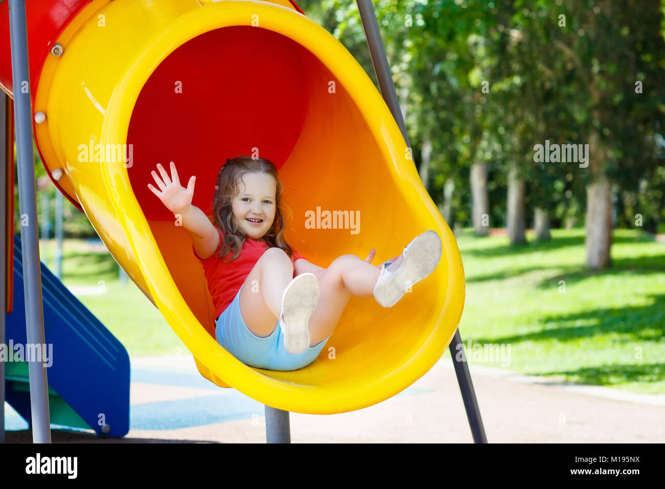 Kids climbing and sliding on outdoor playground. Children play in sunny summer park. Activity and amusement center in kindergarten or school yard. Chi Stock Photo