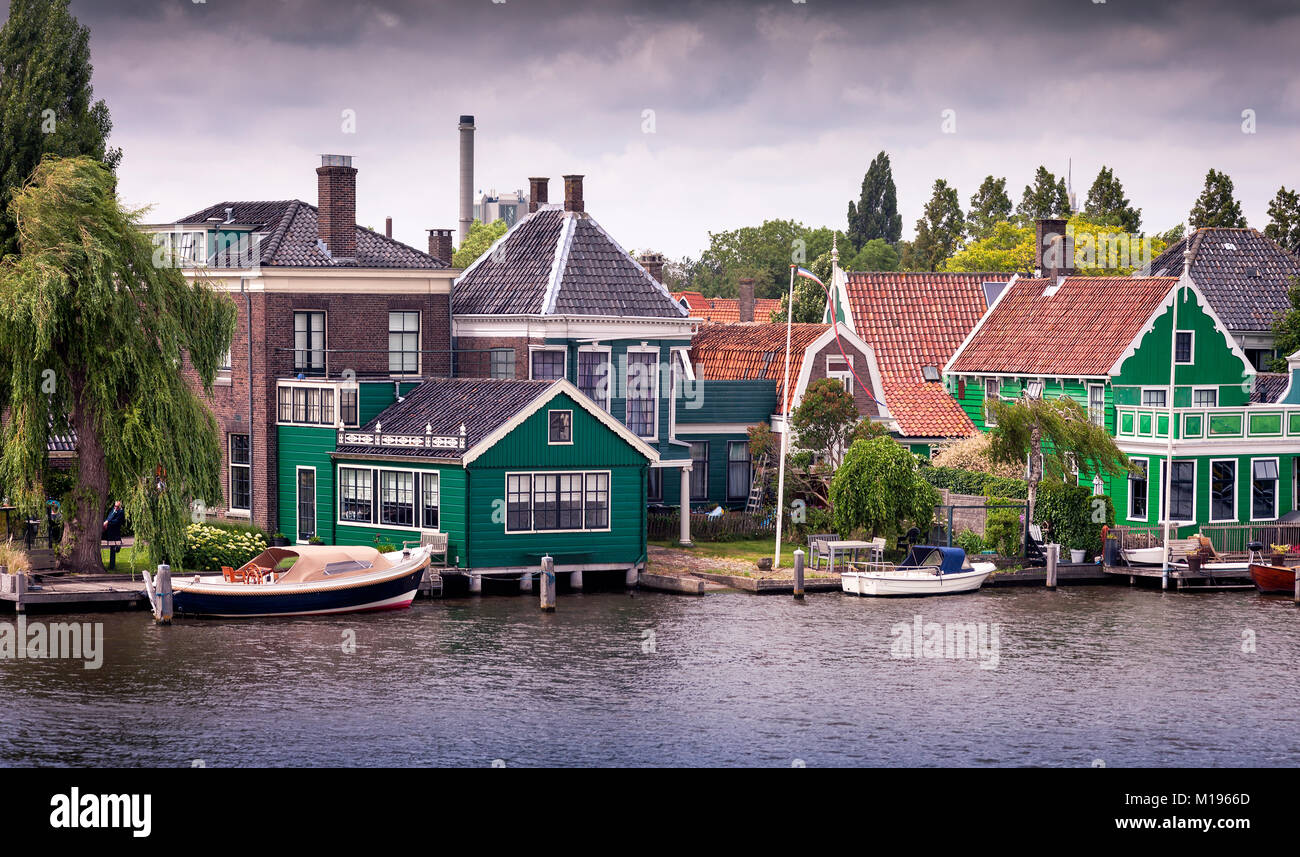 Dutch windmills and houses on the Zaans river from Zaanse Schans National Park and Museum in North Holland Stock Photo