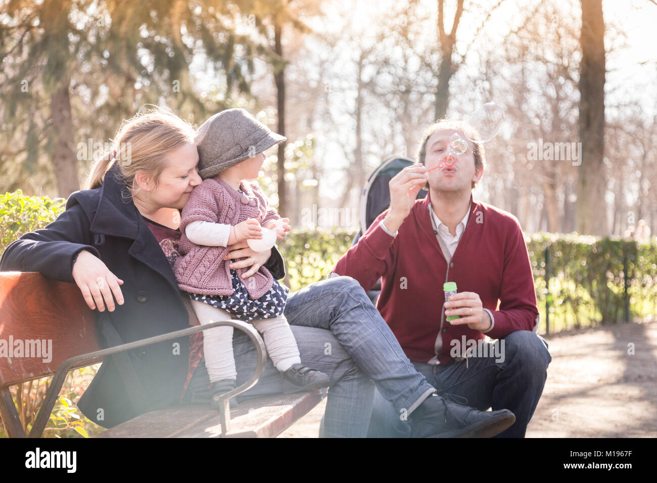 Young happy family with cheerful child having fun in park on sunny day ...