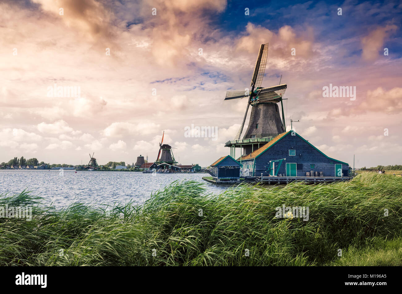 Dutch windmills and houses on the Zaans river from Zaanse Schans National Park and Museum in North Holland Stock Photo