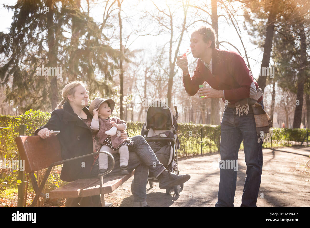 Young happy family with cheerful child having fun in park on sunny day ...