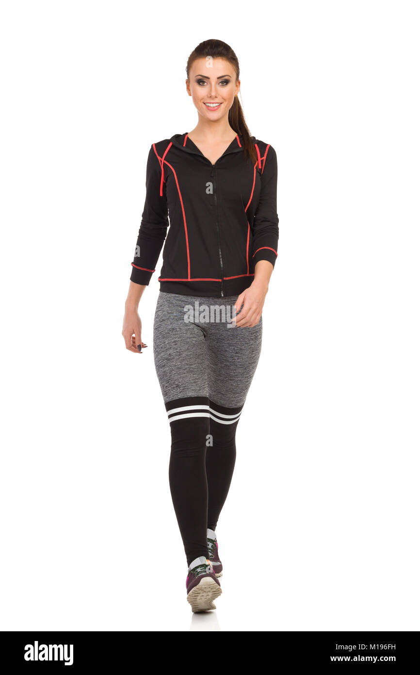 Beautiful young woman in sports clothes and leggings is walking towards  camera, smiling and looking away. Front view. Full length studio shot  isolated Stock Photo - Alamy