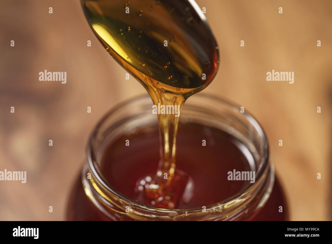 organic honey drips from spoon in jar Stock Photo
