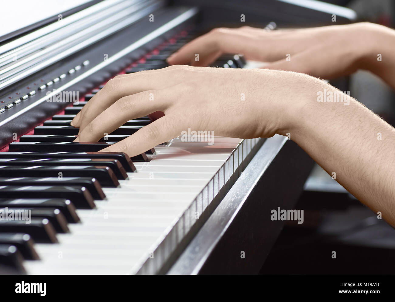 Wooden black piano with a keyboard and female hands of a musician, with a blurred background Stock Photo