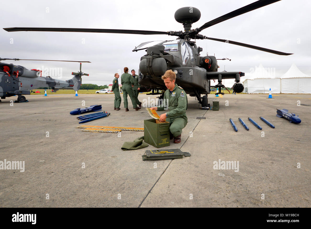 British Army AH-64 Apache gunship with crewman loading gun shells into an ammunition box. Weapons. Defense industry. Military personnel, crew Stock Photo
