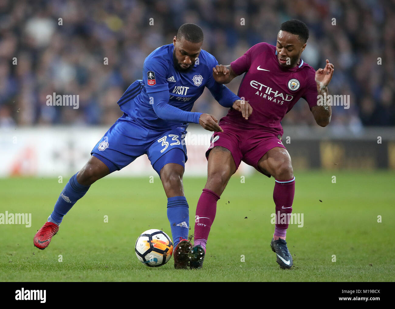 Cardiff City's Junior Hoilett (left) and Manchester City's Raheem Sterling battle for the ball during the Emirates FA Cup, Fourth Round match at Cardiff City Stadium. Stock Photo