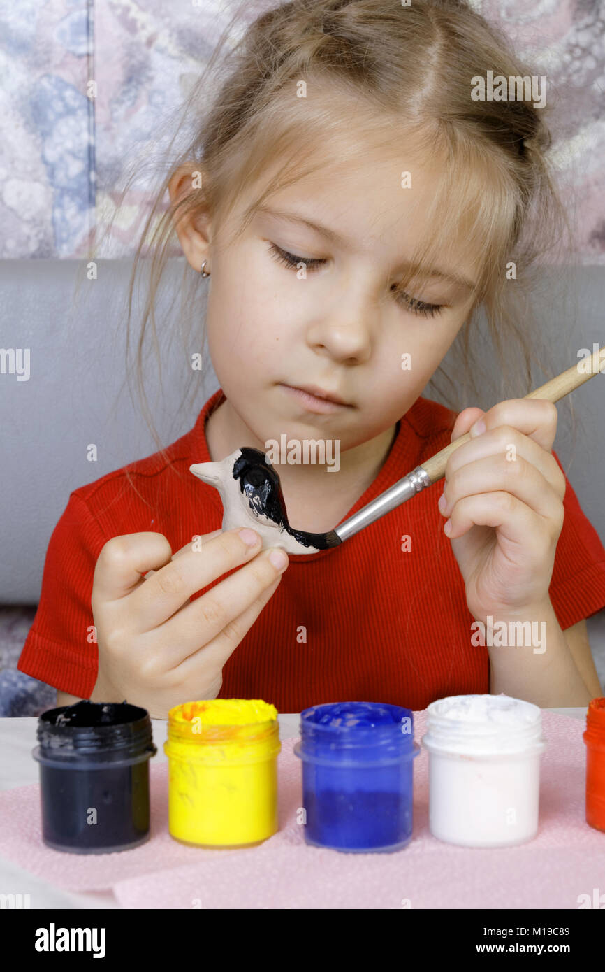 Girl paints her crafts (focus on brush). Diligence and attention to the process Stock Photo