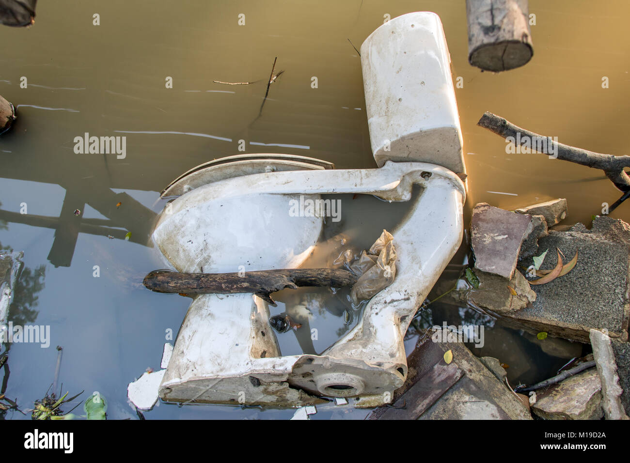 An old toilet bowl is in the water. River waste, Thailand. Stock Photo