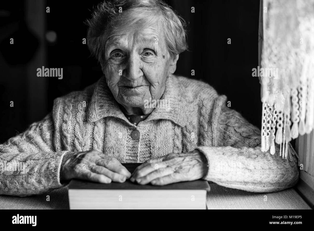 Black-and-white portrait of an elderly woman with a big book. Stock Photo