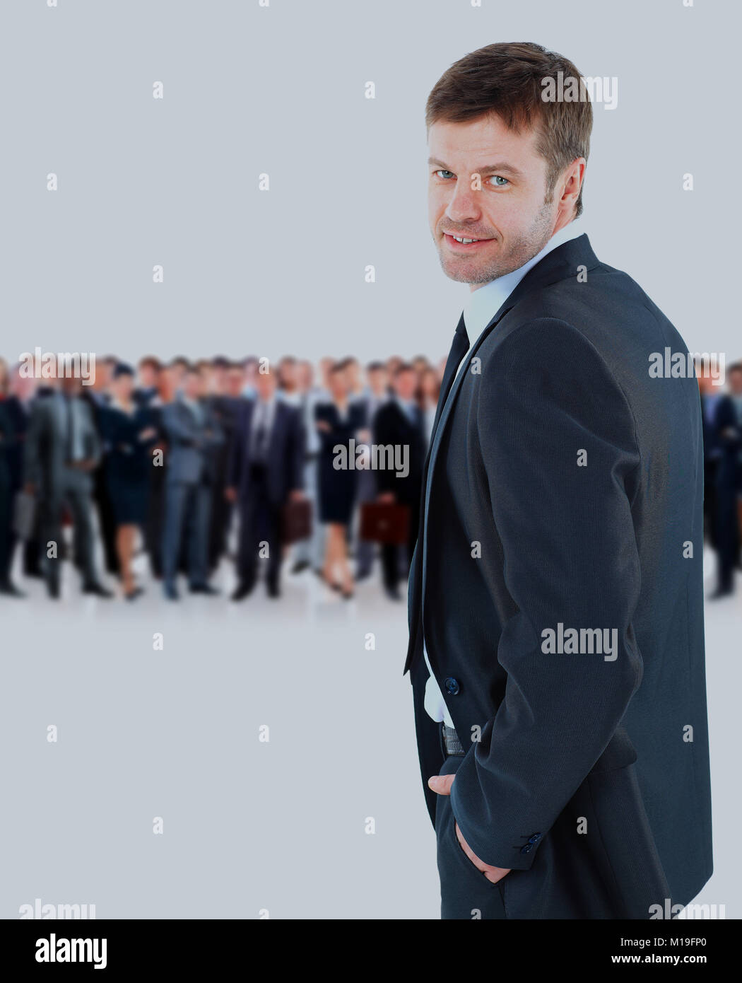 young businessman turned back, looking at the camera and smiling on the background of his team. Stock Photo