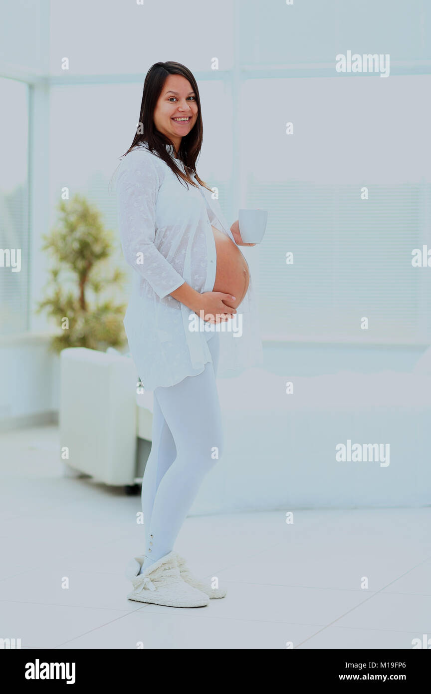 Pregnant woman standing and holding a cup Stock Photo - Alamy