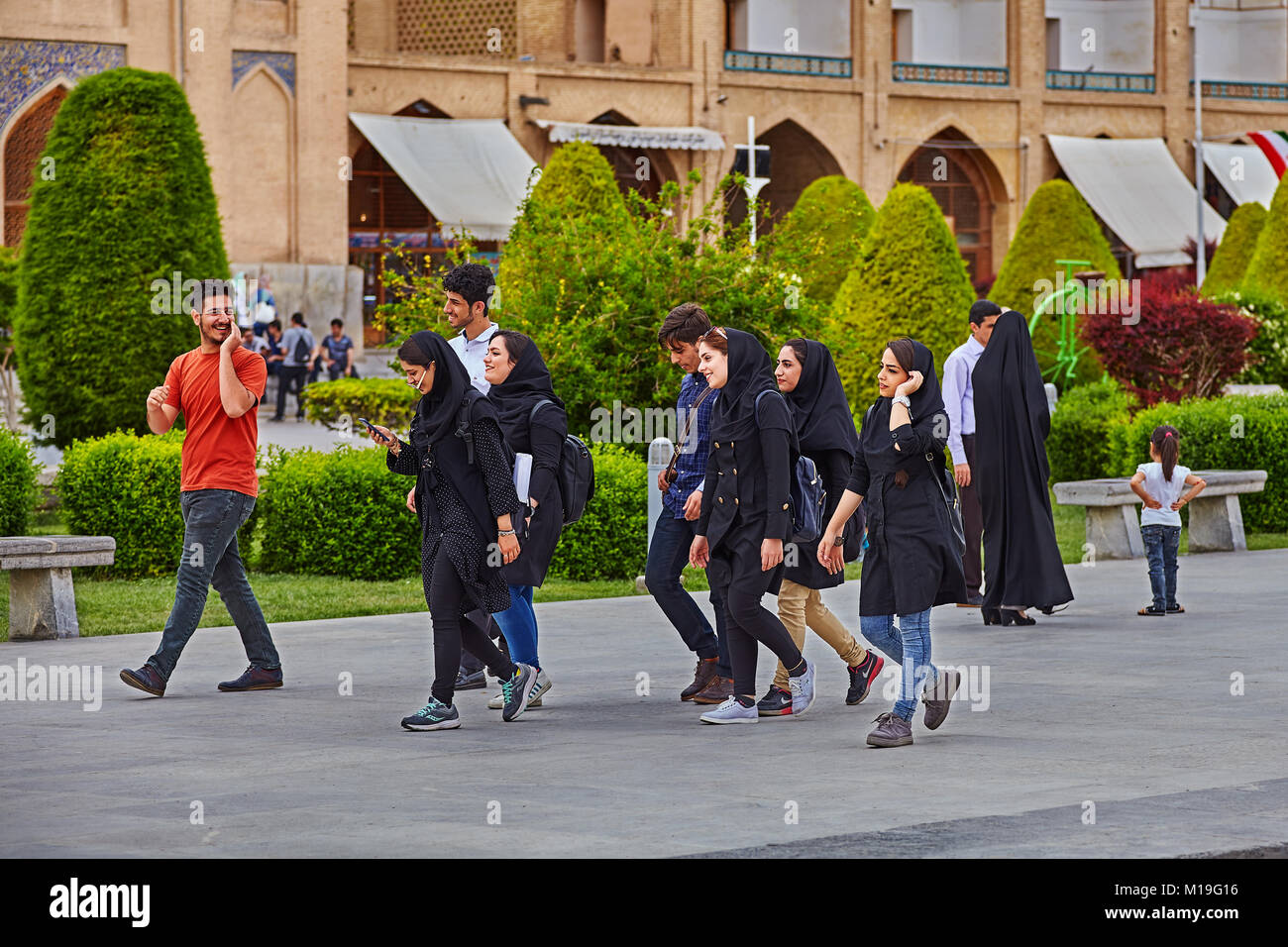 Isfahan, Iran - April 24, 2017: Several young men and women, college-age, go over the area Naghsh-e Jahan, and talking cheerfully. Stock Photo