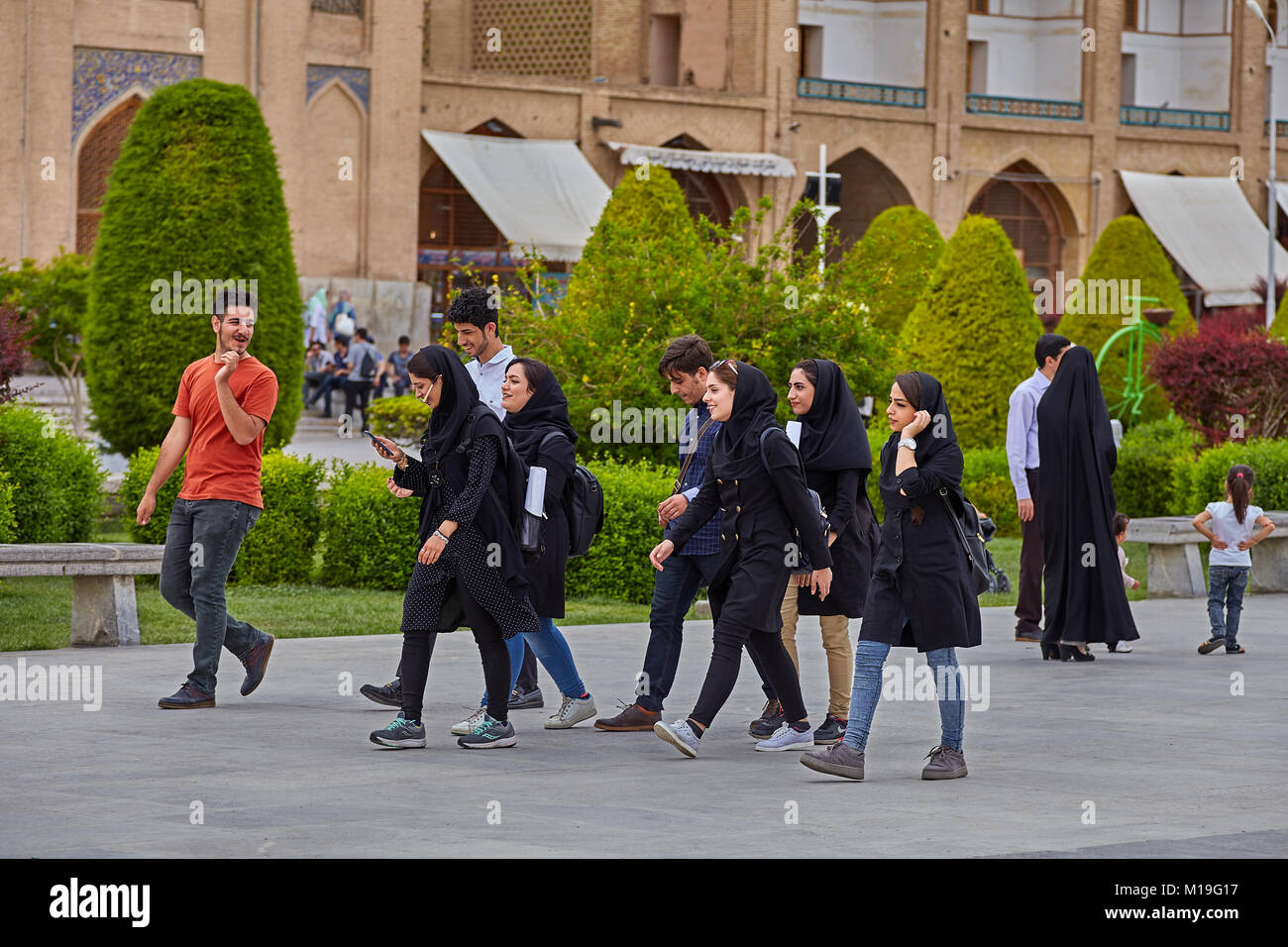 Isfahan, Iran - April 24, 2017: Group of boy and girl, college age, walk along Imam Square, and chat gaily. Stock Photo