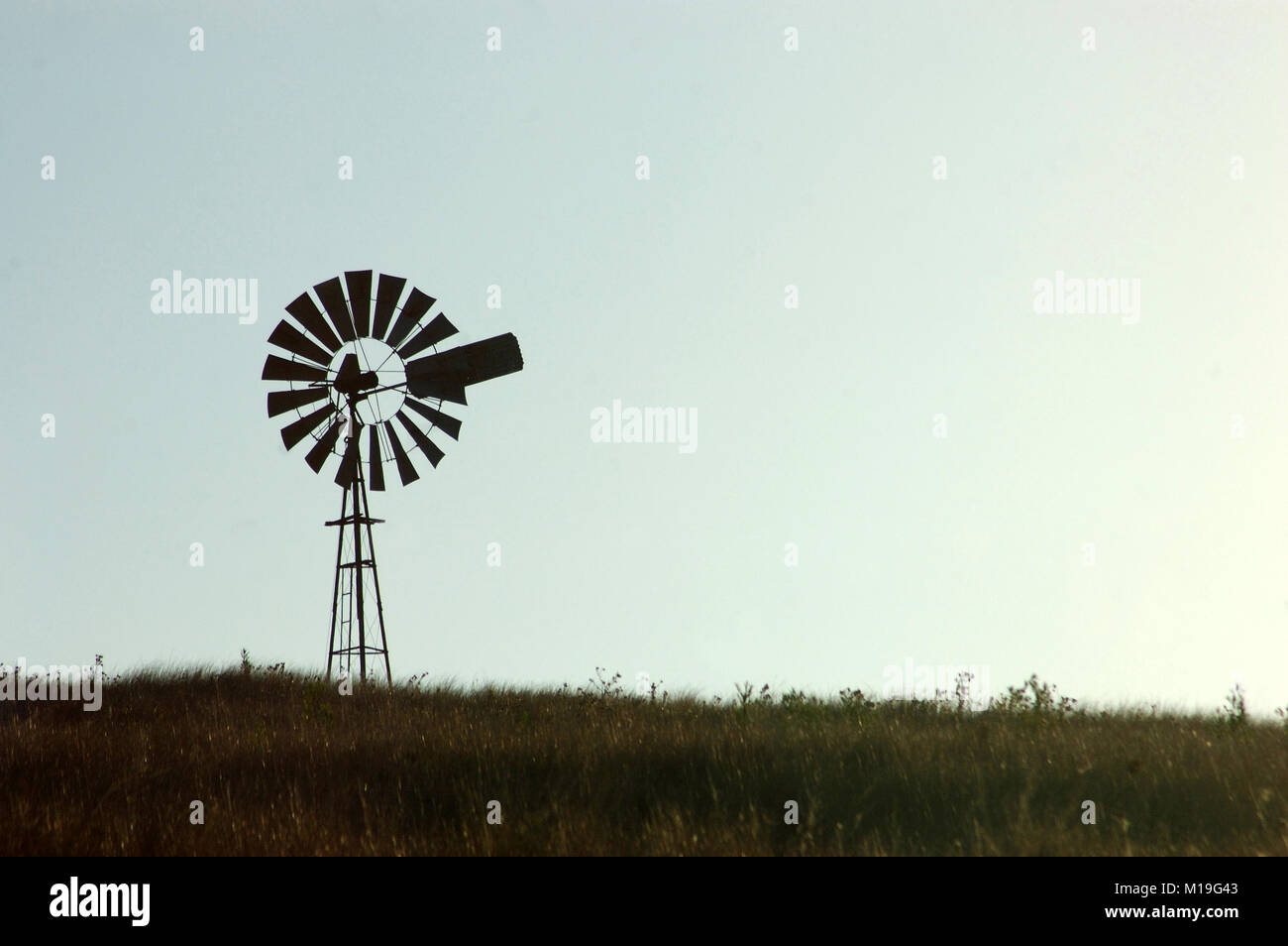 Silhouette of windmill in paddock, Queensland, Australia. Windmills are commonly used for pumping water from bores or dams to troughs for livestock. Stock Photo