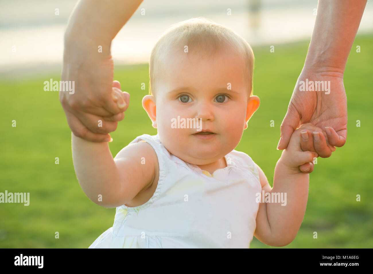 Portrait Of A Cute Baby Girl's Hand Hold By Her Mother At Outdoors Stock Photo