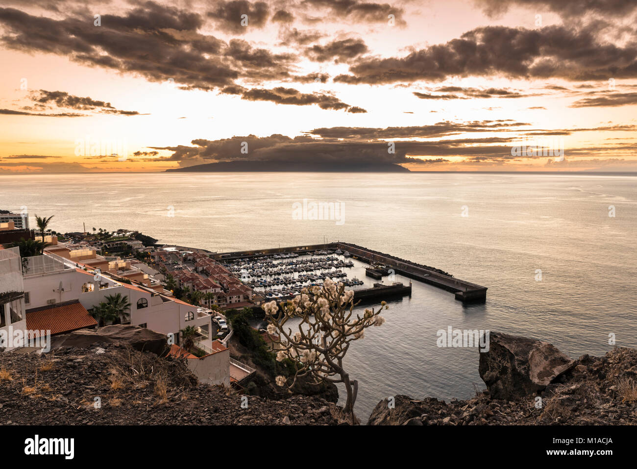 View westwards at sunset over the harbour of Los Gigantes, Tenerife, Canary Islands towards the island of La Gomera  with spectacular sky and calm sea Stock Photo