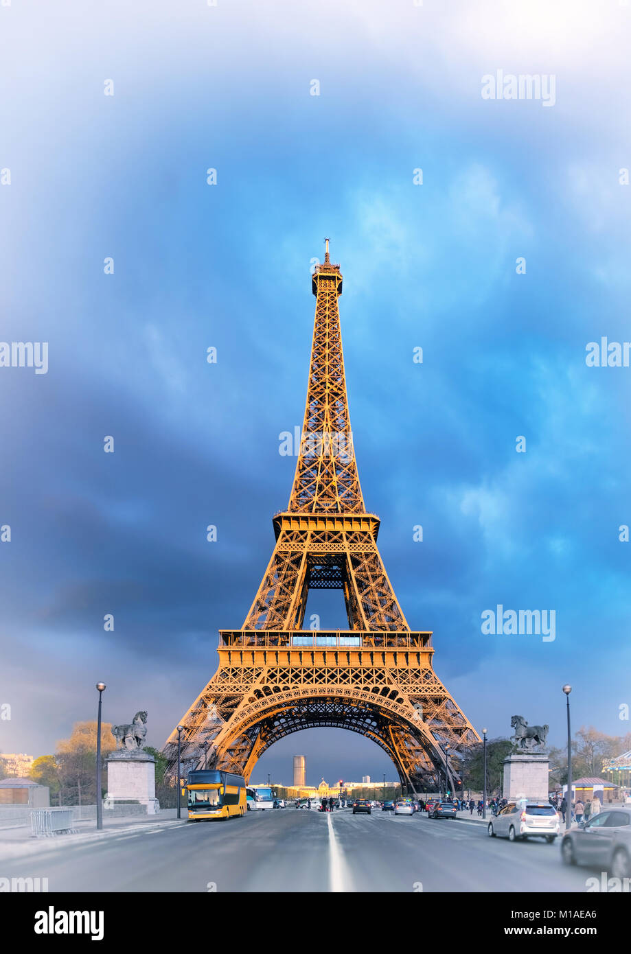 Eiffel Tower on a stormy evening with the last rays of setting Sun shining between the clouds. Panorama made from four horizontal images. This image i Stock Photo