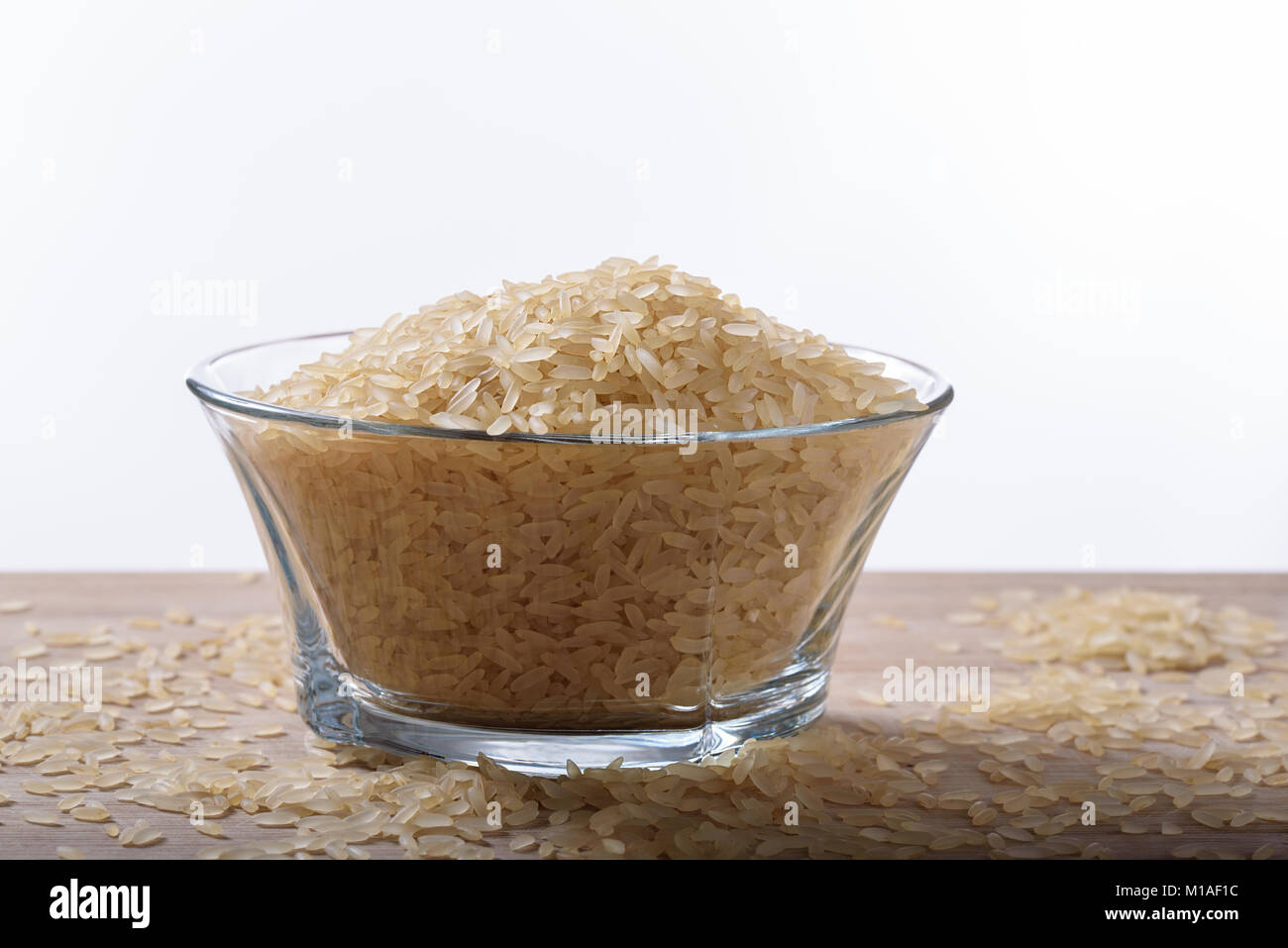 Bowl of uncooked parboiled rice side view with white background Stock