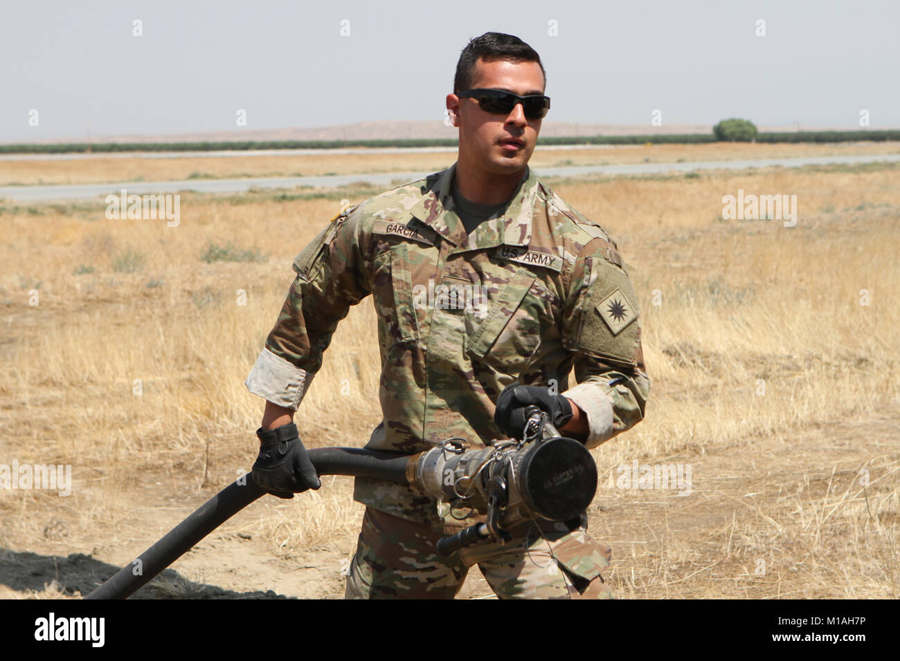 Pfc. Vicente Garcia from Echo Company, 1st Battalion, 140th Aviation Regiment, California Army National Guard, stretches a fuel pump to a UH-60 Black Hawk July 13 at Coalinga Municipal Airport, Fresno County, California, as CalGuard air assets were called to battle the Garza Fire in mid-July 2017. (Army National Guard photo/Staff Sgt. Eddie Siguenza) Stock Photo