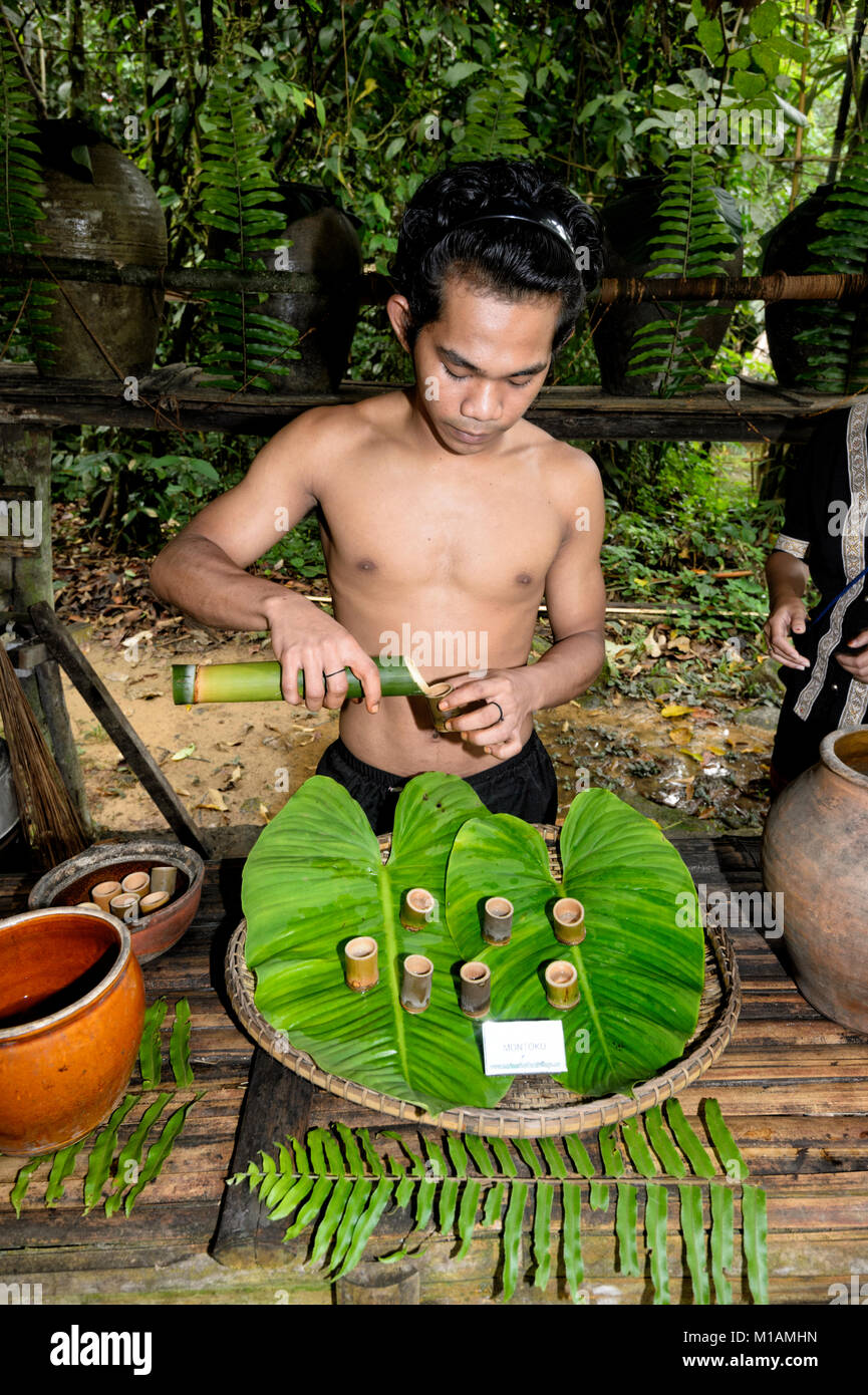 Young Malaysian man serving rice wine in traditional bamboo containers