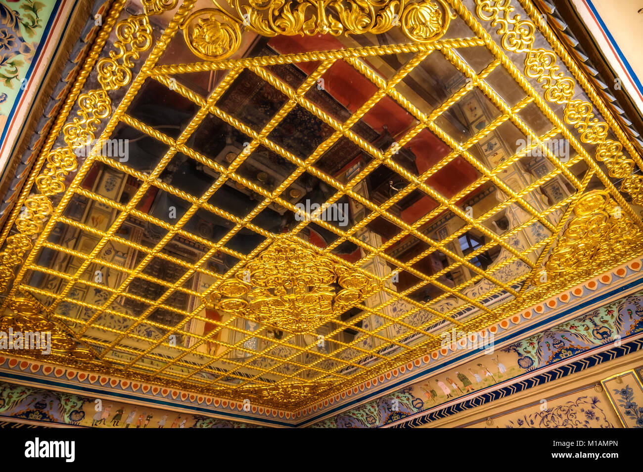 Royal Palace room ceiling at Patwon ki Haveli Jaisalmer with intricate gold artwork and mirrors. Stock Photo